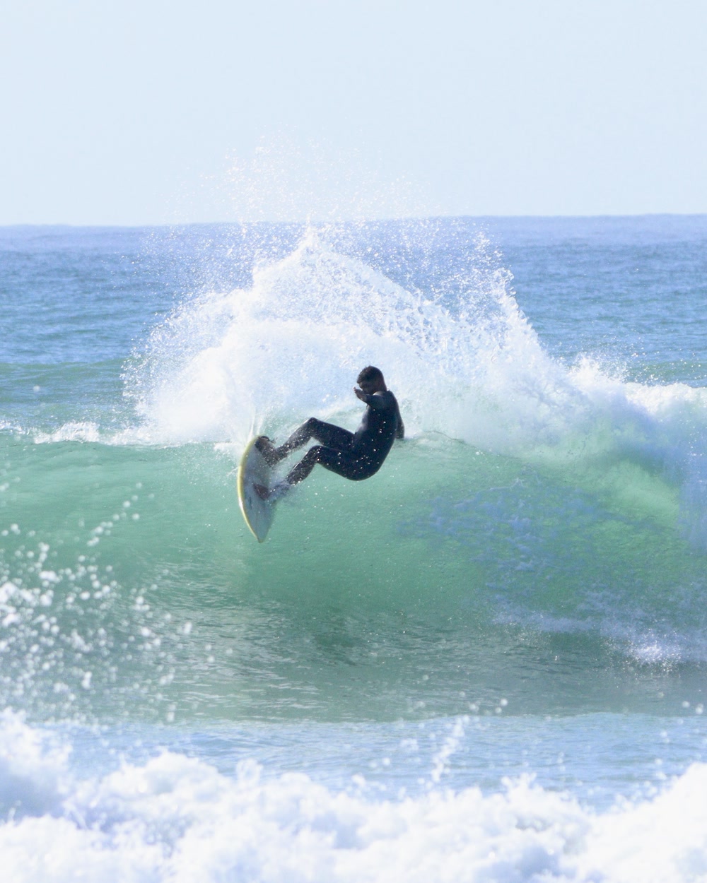Surfer leaning into a laid-back carve at Jeffreys Bay, spray thrown off the top