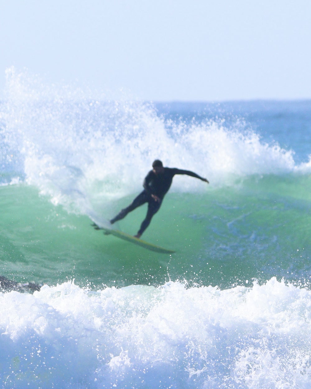 Surfer coming off the top of a wave under a folding lip at Jeffreys Bay