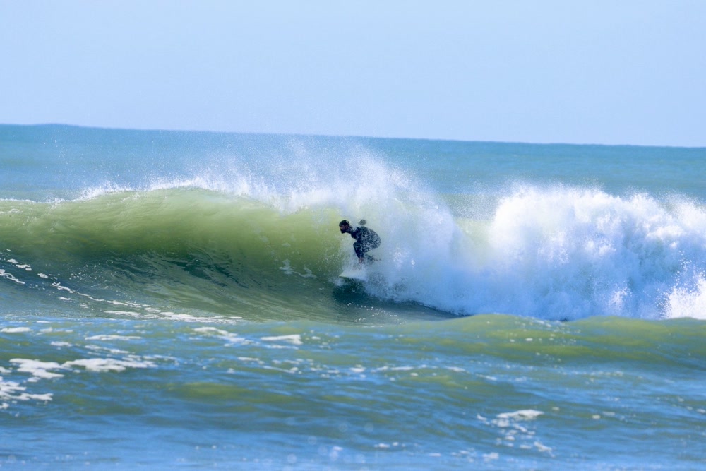 Barrel sequence at Jeffreys Bay, frame 1: the surfer crouches as the wave stands up hollow