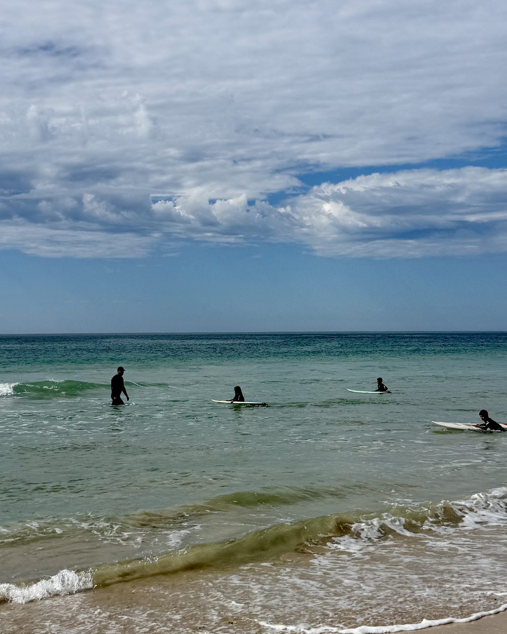 Dramatic clouds over the Jeffreys Bay shoreline as surfers wade in
