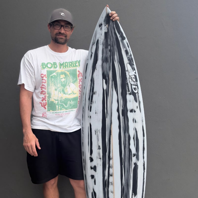 A surfer holding his marbled black and white custom Paul Jeggels Designs board